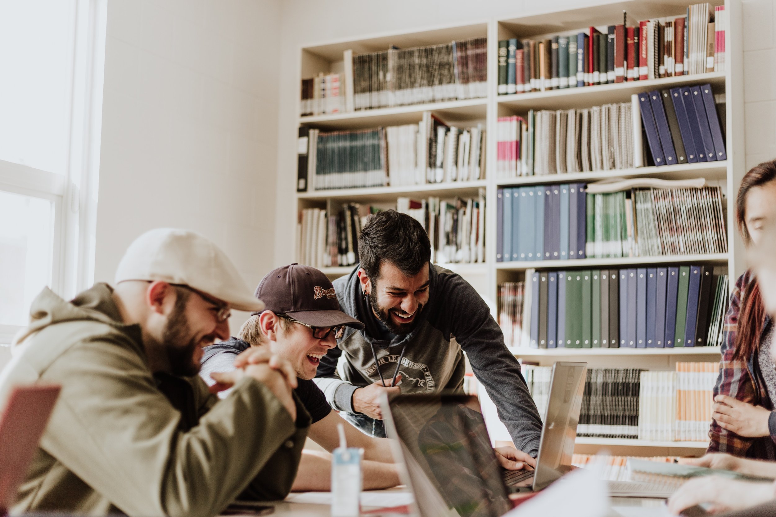 Image of colleagues in a library laughing at what they are looking at on one of their screens