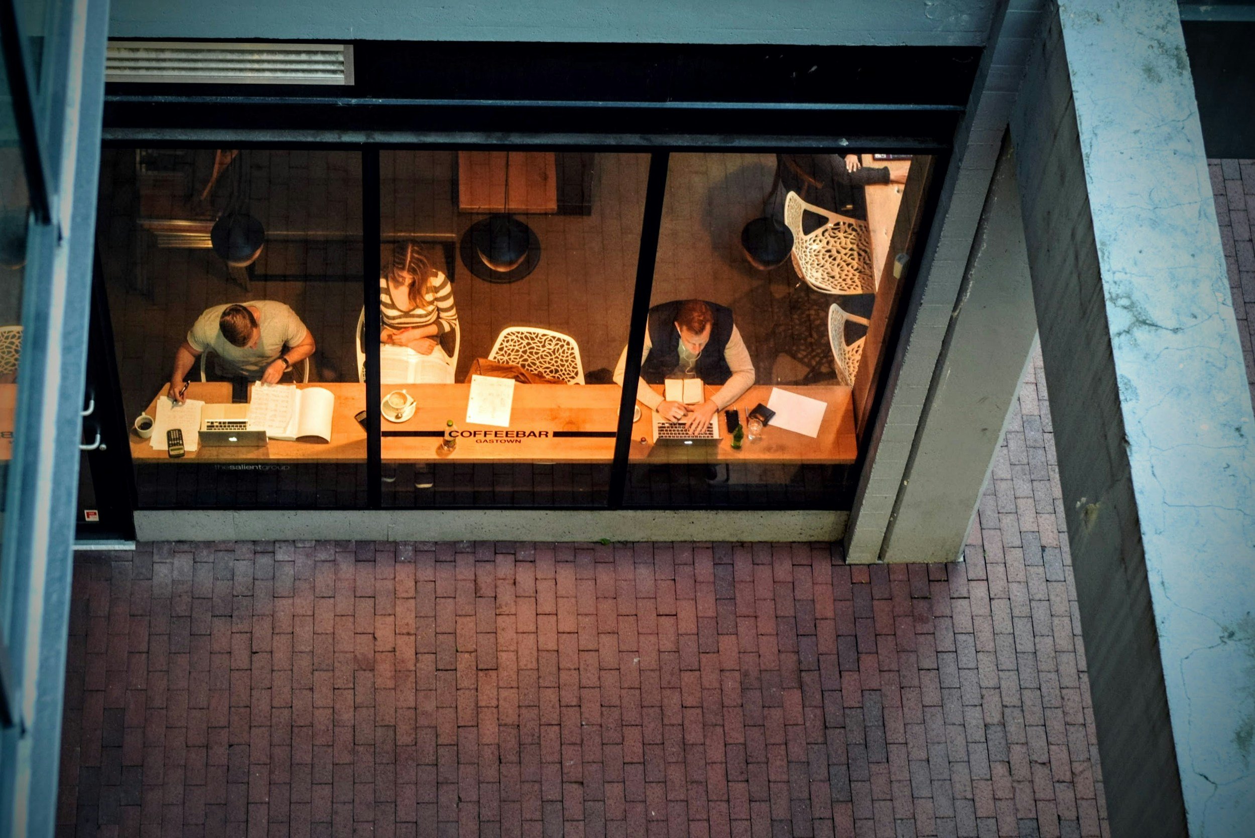 Overhead picture of professionals working at a coffee shop on their laptops