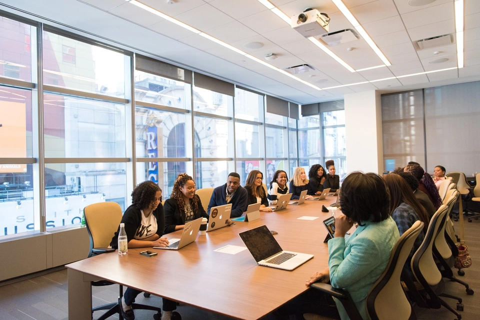 Office meeting room filled with people on their laptops working together