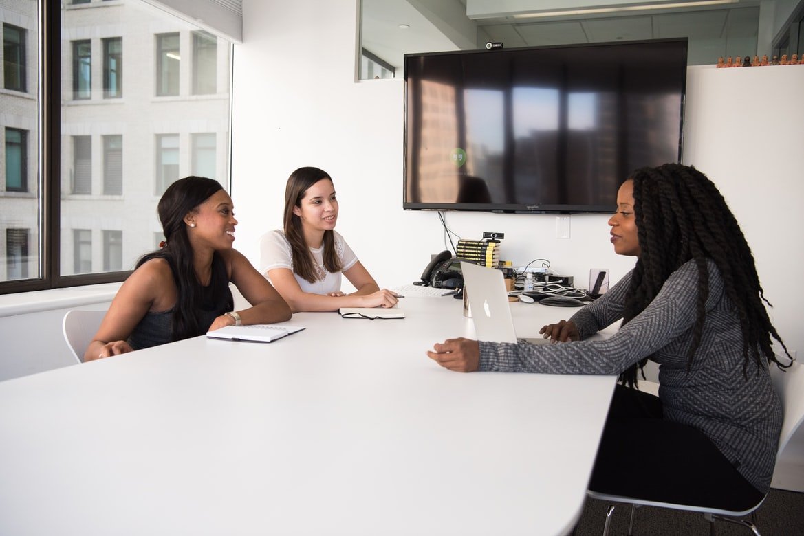 Two recruiters interviewing a woman in a small office room